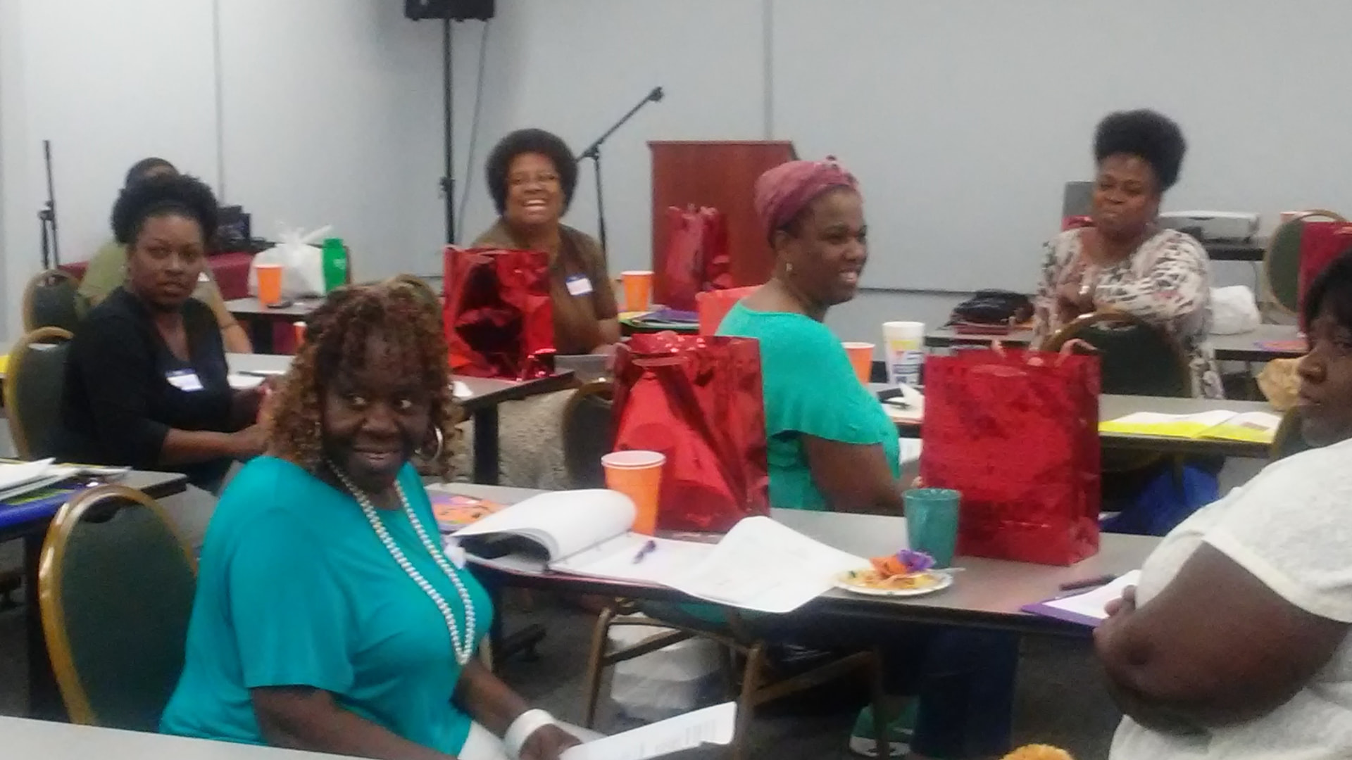 Participants smiling with red gift bags on the workshop tables